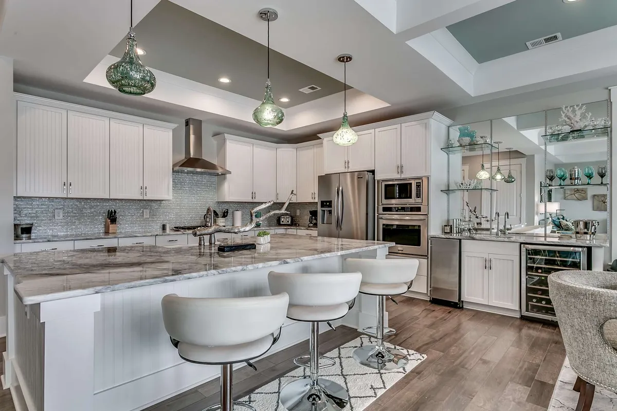A spacious, modern kitchen with a large island, elegant pendant lighting, and stainless steel appliances. The open layout invites socializing and gathering, emphasizing upscale comfort and the pleasures of shared meals or entertaining small groups.