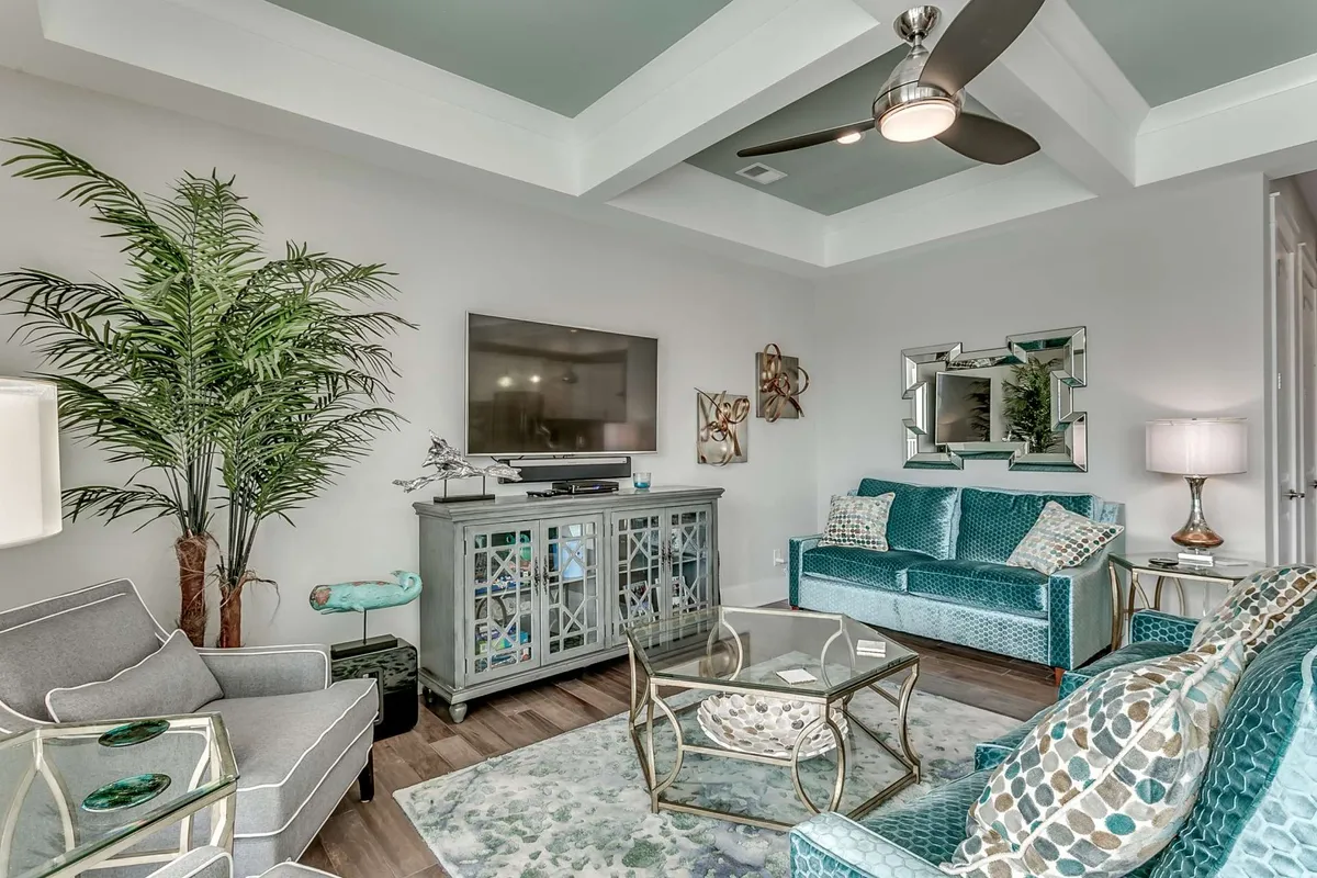 A cozy living space with a plush sofa, a coffee table, a television, and a palm plant. The room is bathed in natural light, offering a relaxing spot for unwinding, watching movies, or spending quality time with friends and family.