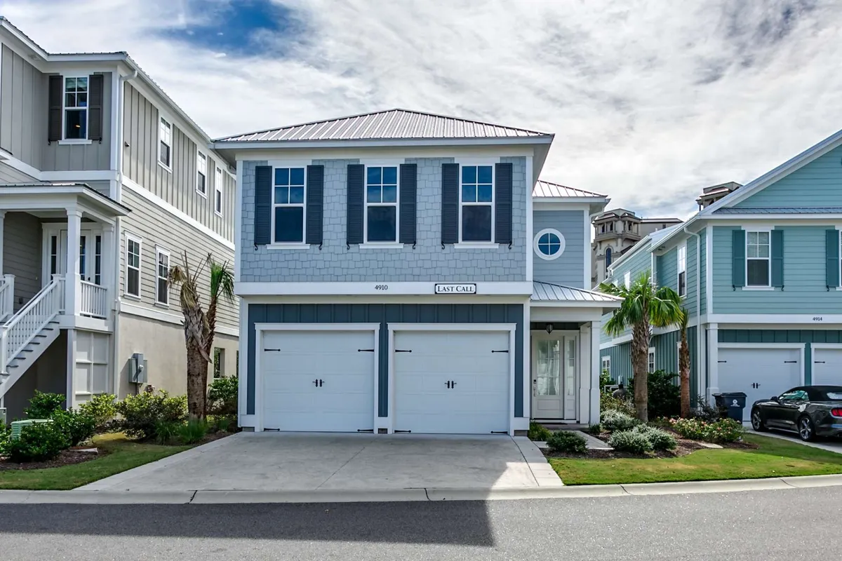 A welcoming exterior view of a two-car garage home with a front porch surrounded by palm trees and lush landscaping. The porch is ideal for casual gatherings, and the home's facade suggests a family-friendly, beach-close environment.